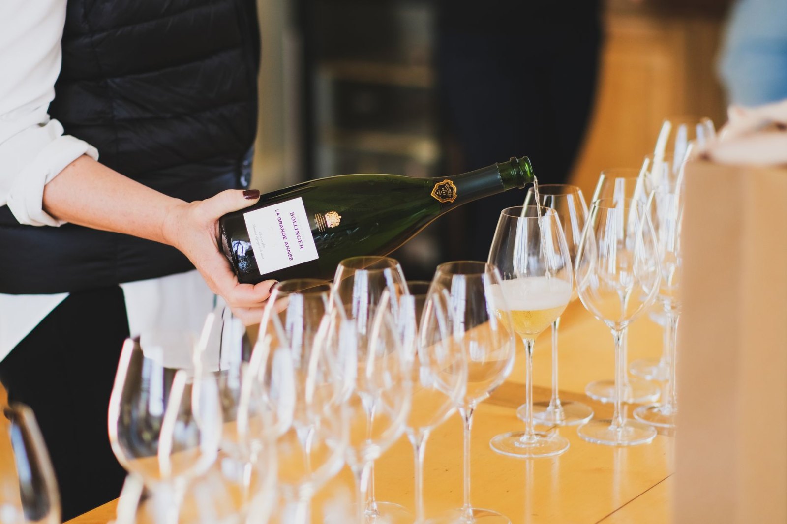 Бутылка Dom Perignon в чёрной упаковке стоит на тёмном велюровом подиуме, драматическое освещение сверху создаёт глубокие тени, минималистичная композиция на чёрном фоне